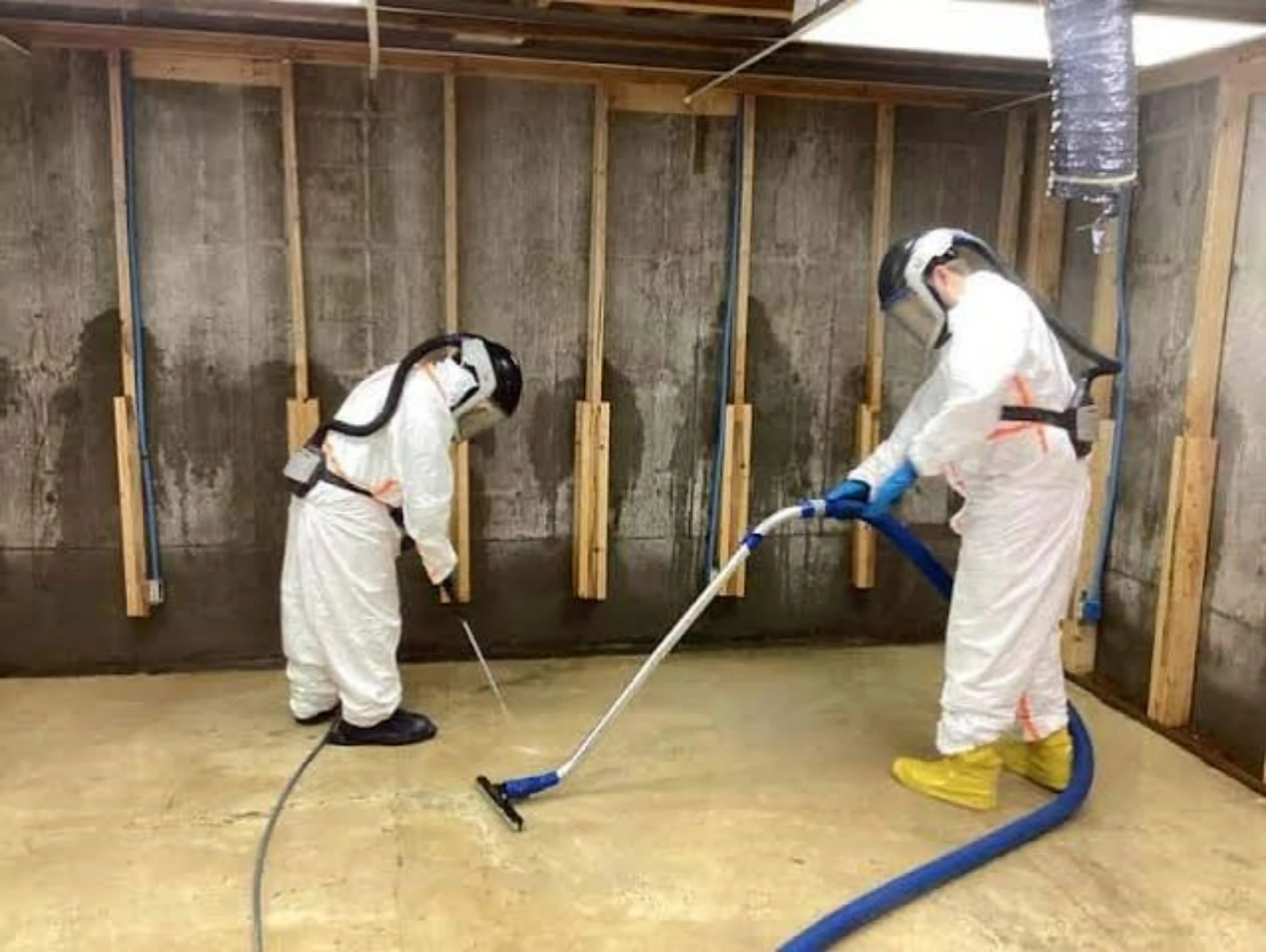Hazardous sewage cleanup technicians extracting contaminated wastewater in protective gear